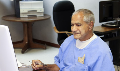 Smiling man sits in front of computer screen