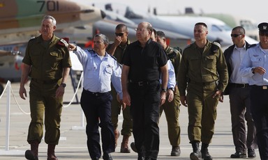 A group of men in uniforms walk in front of warplanes