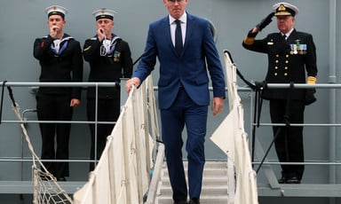 Simon Coveney walks on steps surrounded by three others in naval uniform 