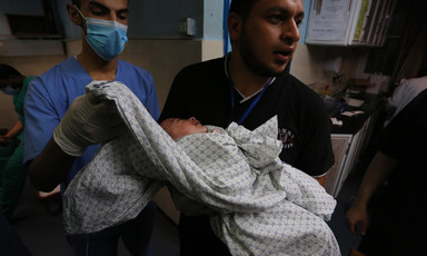 Man holds a baby wrapped in a sheet 