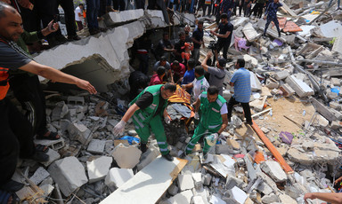 Rescue workers surrounded by rubble carry a stretcher