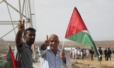 Two men with Palestinian flag make victory sign