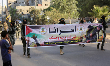 Men dressed in military uniform hold banner 