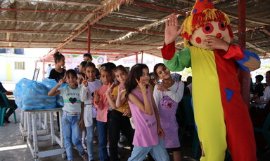 Children play behind a clown