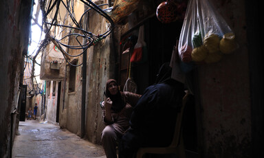 Two women sit outside a shop 