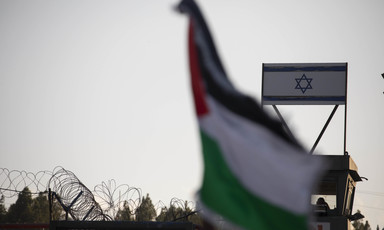 A Palestinian flag flutters in front of an Israeli flag