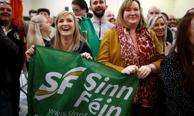 Smiling people hold Sinn Fein banner