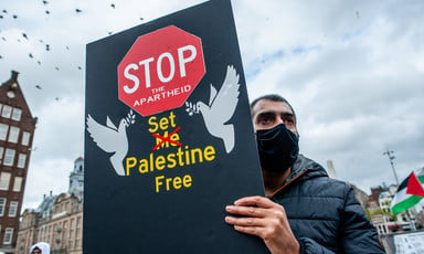 Man wearing face mask holds placard calling for freedom for Palestinians