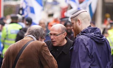 Three men at a demonstration with Israeli flags