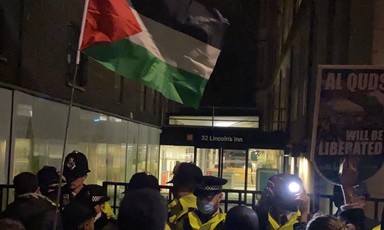 Protesters with a Palestinian flag facing police
