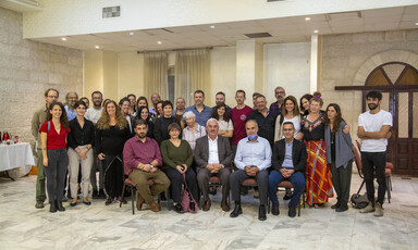 Group photo of people sitting on chairs and standing in conference room