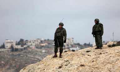 Men in combat gear stand on hilltop