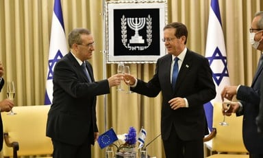Two men raise champagne glasses in front of Israeli flags