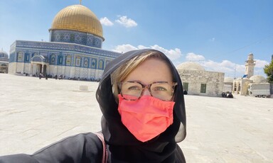 Woman in face mask stands in front of Jerusalem's Dome of the Rock