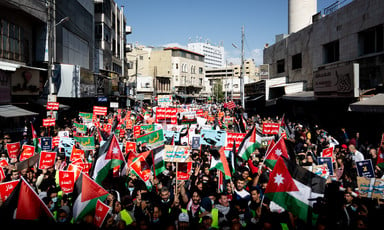 Large crowd holding signs and Jordanian flags