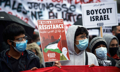 Two men wear masks while holding signs