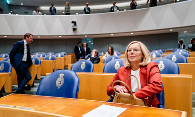 Woman reaches into handbag while sitting in a nearly empty auditorium