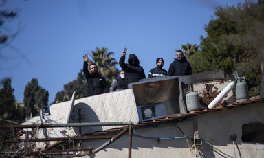 Four men stand on top of a roof 