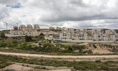 Apartment buildings and cranes against cloudy sky