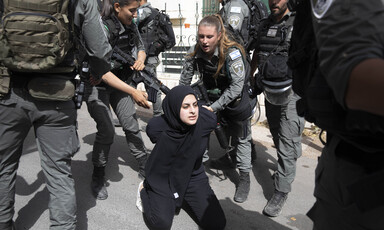 . Armed police grab a woman who is kneeling on the ground