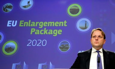 Man stands in front of blue blackdrop with the words EU enlargement package 2020