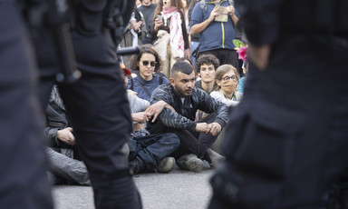 A group of activists sit on the ground surrounded by police 