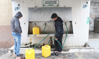 Two boys fill yellow containers with water 