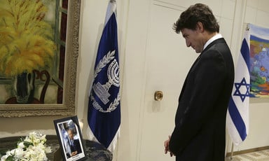 Justin Trudeau looks at a photograph of Shimon Peres next to a bouquet