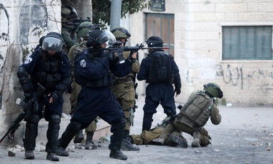 Heavily armed forces take position at a street corner 