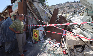 A man standing with arms akimbo looks at taped-off rubble 