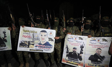 Armed militants hold up their weapons along with posters 