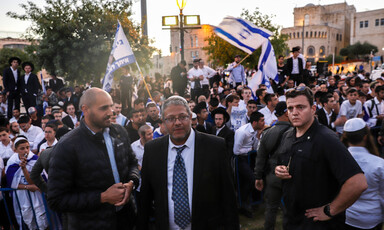 Three men stand in the front while others wave flags behind them 