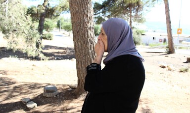 Woman stands beside a tree 