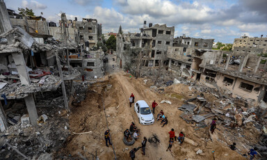 Aerial view of car driving on road lined by bombed-out buildings