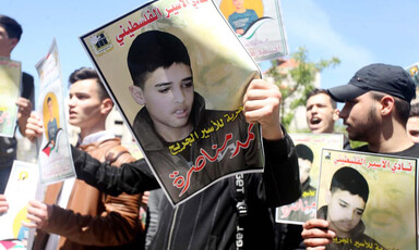 Protestors hold up a poster of a young boy calling for his release from Israeli prison