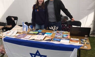 A woman and a man at a stall draped in an Israeli flag