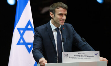 Macron stands at podium beside flag of Israel