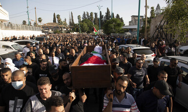 People carry a body wrapped in a flag in a coffin
