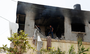 People inspect a damaged house with smoke-stained walls 