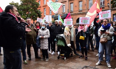 A man with a microphone addresses people holding signs in a street