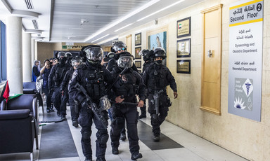 Men in right gear walk through hospital corridor