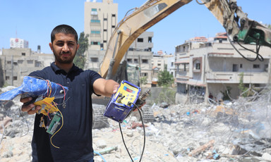 A man shows off what he has found in the rubble of a building