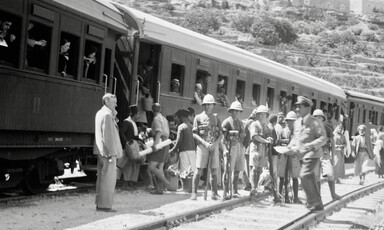 Carriages with people inside and outside and a row of soldiers in helmets