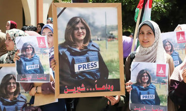 Young women hold posters and Palestinian flag