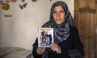 A woman holds a photograph in front of her