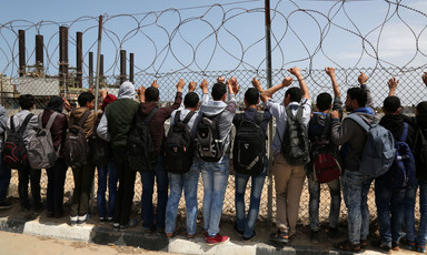 Palestinian students look through barbed wire at power plant