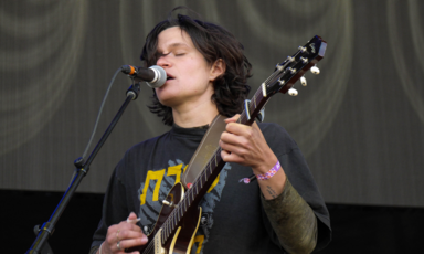 Woman plays the guitar and sings on a microphone 