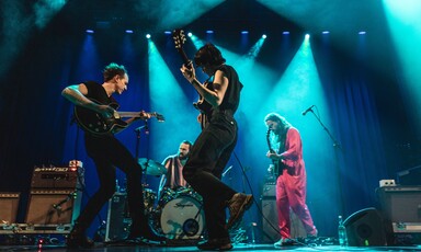 Band performs on stage with colorful lights 
