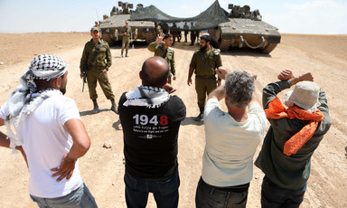A group of young men confronts soldiers standing beside tanks 