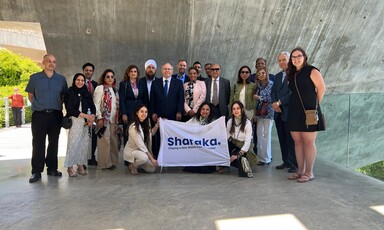 Group of people pose with a banner that says "Sharaka" 